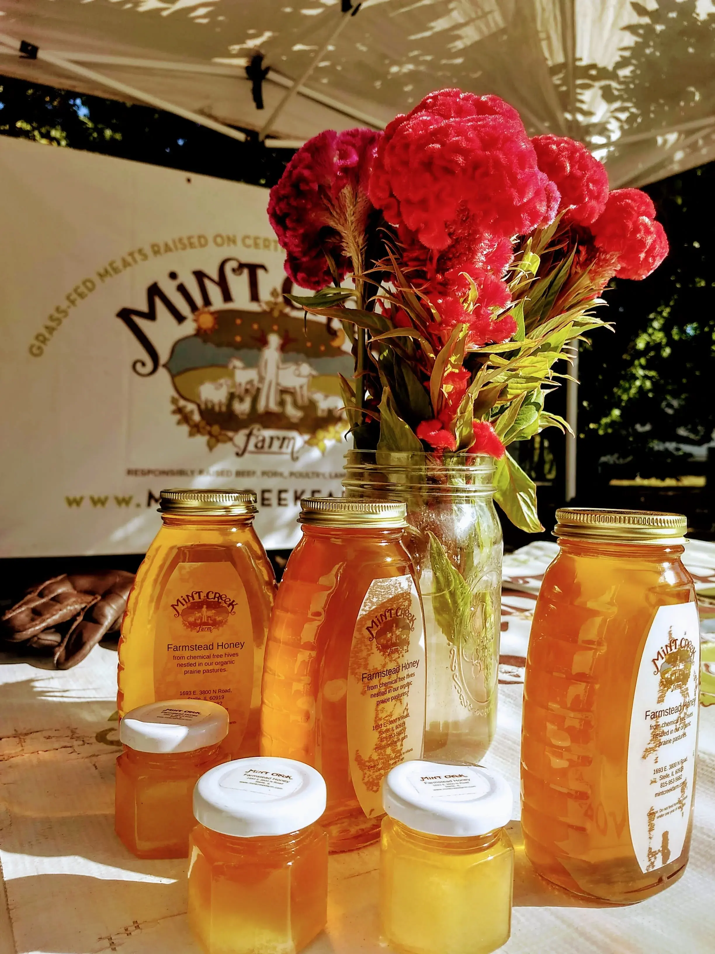 Jars of honey and vase of flowers at farmers’ market booth
